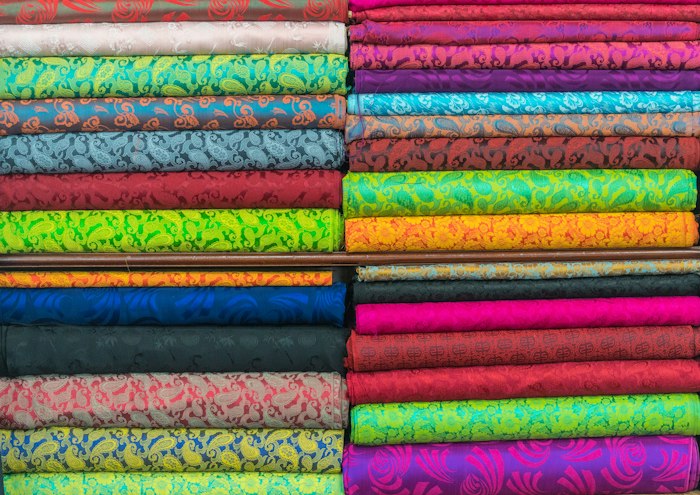 Bolts of patterned fabric stacked in a shop