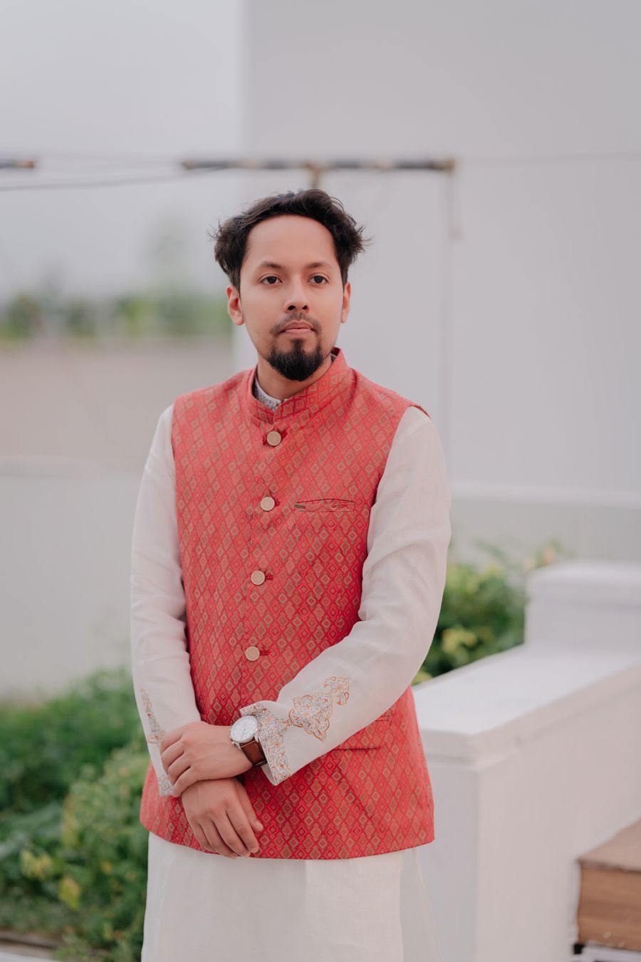 Young man in a coral Nehru jacket over a white kurta