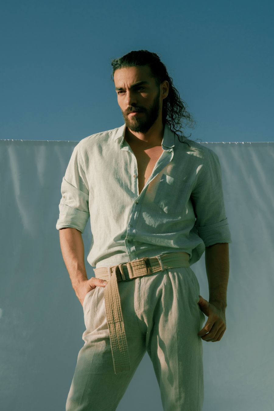 Man with curly hair in an open-collar linen shirt