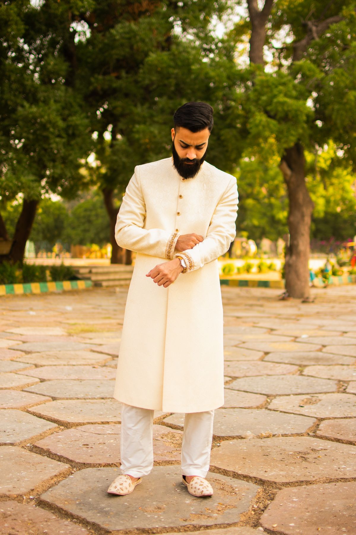Man in an ivory embroidered kurta set adjusting his cuff