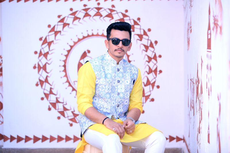 Man in sunglasses wearing an ivory Nehru jacket over a yellow kurta