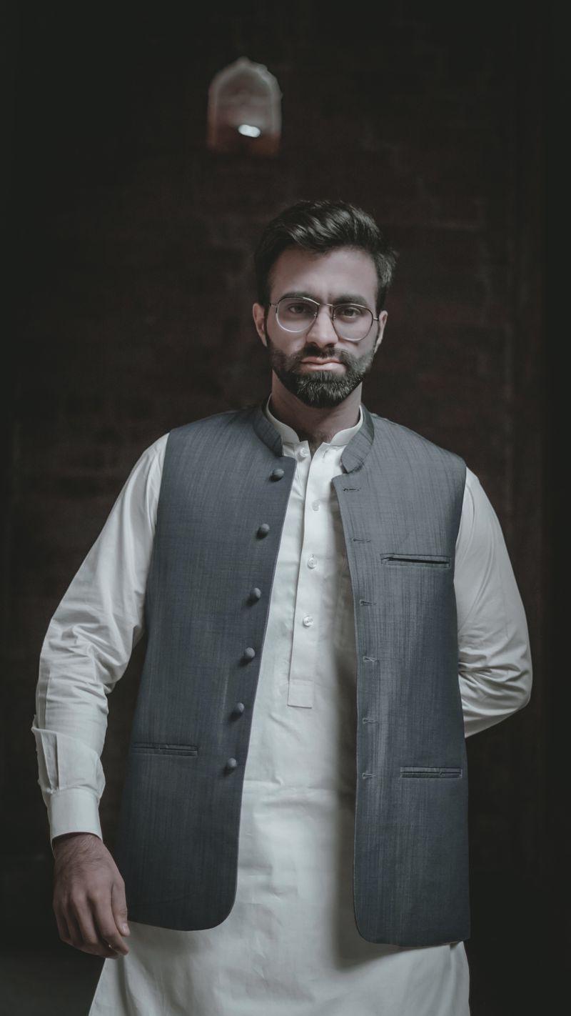Man in glasses wearing a grey Nehru jacket over a white kurta