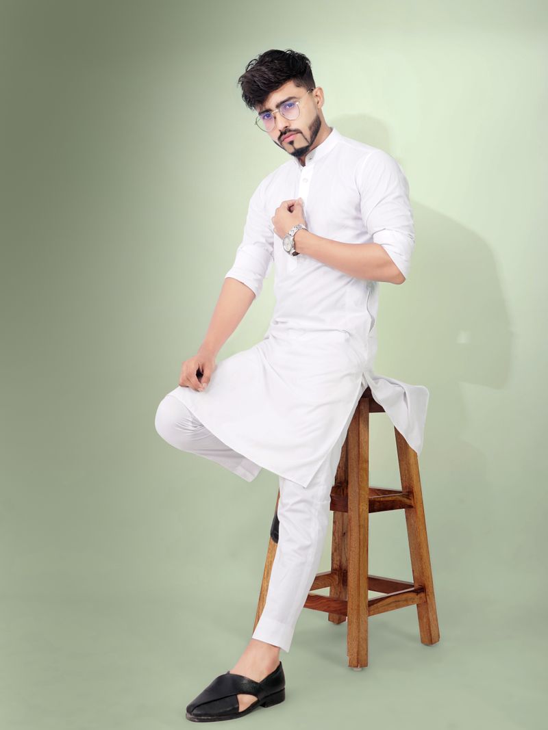 Young man in a white cotton kurta seated on a stool