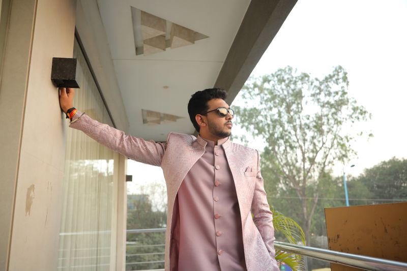 Man in a peach festive kurta set with arms outstretched